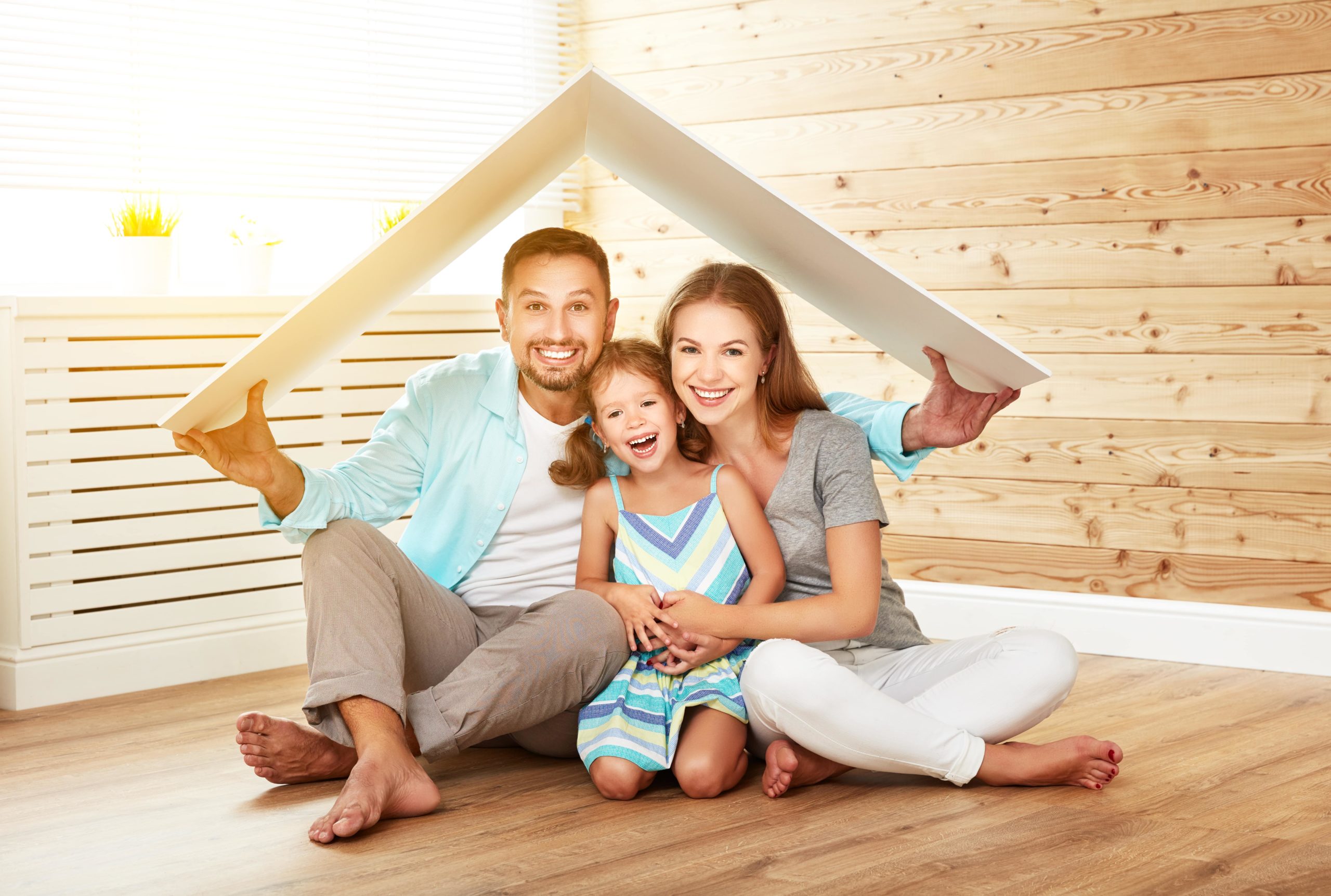 man holding small roof over himself, wife and daughter